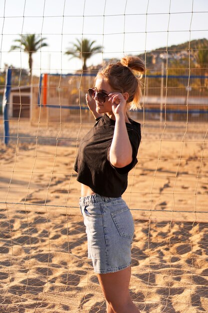 Portrait de femme attirante près du filet de volley-ball sur la photo verticale de plage