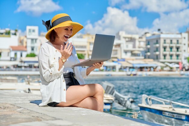 Portrait de femme au chapeau avec ordinateur portable parlant sur la communication vidéo à l'aide d'un ordinateur portable