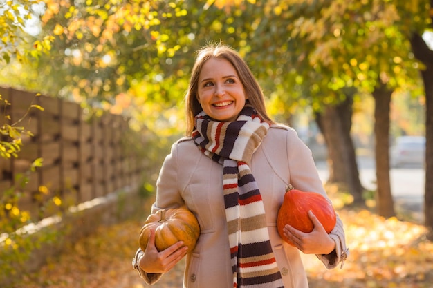 Portrait d'une femme au sourire heureux avec des citrouilles à la main