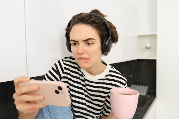 Portrait d'une femme au visage sérieux regardant son smartphone avec une émotion tendue regardant intéressant