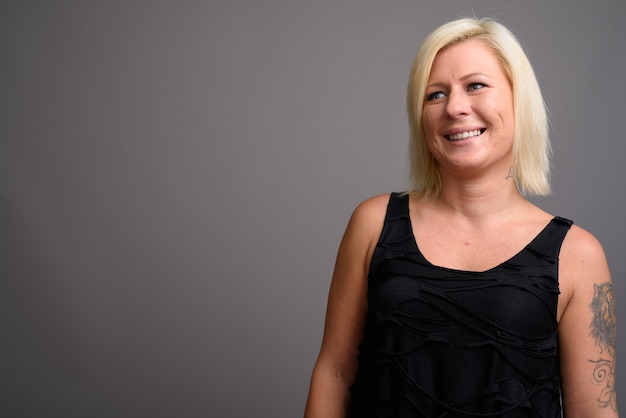 Portrait de femme aux cheveux blonds contre un mur gris