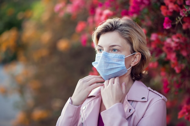 Un portrait de femme aux cheveux blonds courts avec masque facial médical en plein air. Concept de personnes, de soins de santé et de médecine.