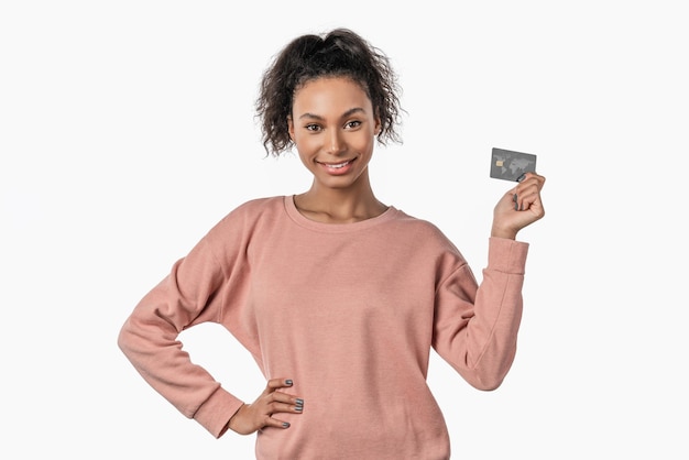 Portrait de femme aux cheveux bouclés tenant une carte de crédit en plastique et souriant