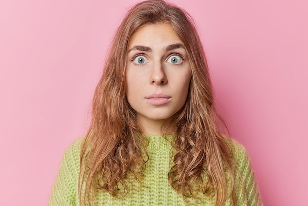 Portrait D'une Femme Aux Cheveux Longs Perplexe Et Choquée Regarde Avec Les Yeux Largement Ouverts à La Caméra Ne Peut Pas Croire En Une Horrible Relation Porte Un Pull En Tricot Vert Isolé Sur Fond Rose Réactions Humaines