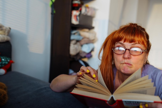 Portrait d'une femme aux cheveux roux lisant un roman