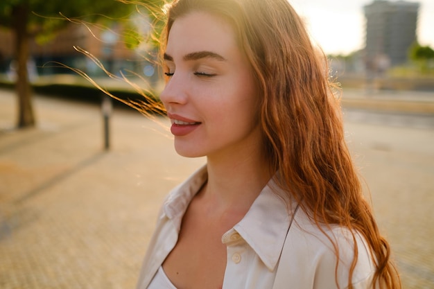 Photo portrait d'une femme aux cheveux roux en profil avec les yeux fermés appréciant la vie