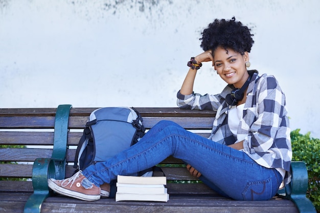 Photo portrait de femme et banc universitaire avec un livre pour l'éducation ou la lecture de l'étude de diplôme visage de personne féminine et étudiant sur le campus universitaire ou à l'extérieur pour une bourse de connaissances ou de la littérature de recherche