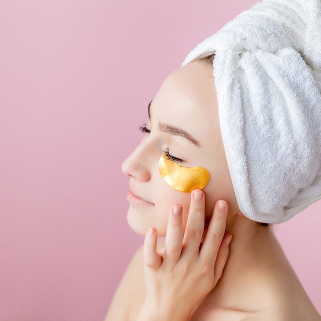 Portrait de femme de beauté avec des pansements oculaires sur fond rose