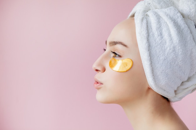 Portrait de femme de beauté avec des pansements oculaires sur fond rose