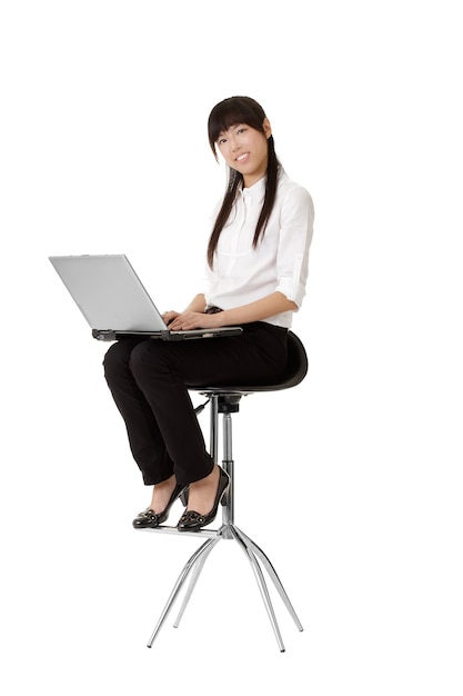 Portrait de femme belle jeune entreprise travaillant et implantation sur une chaise isolée sur un mur blanc.