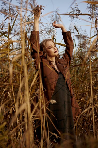 Portrait d'une femme belle mode dans un fourré d'herbe d'automne