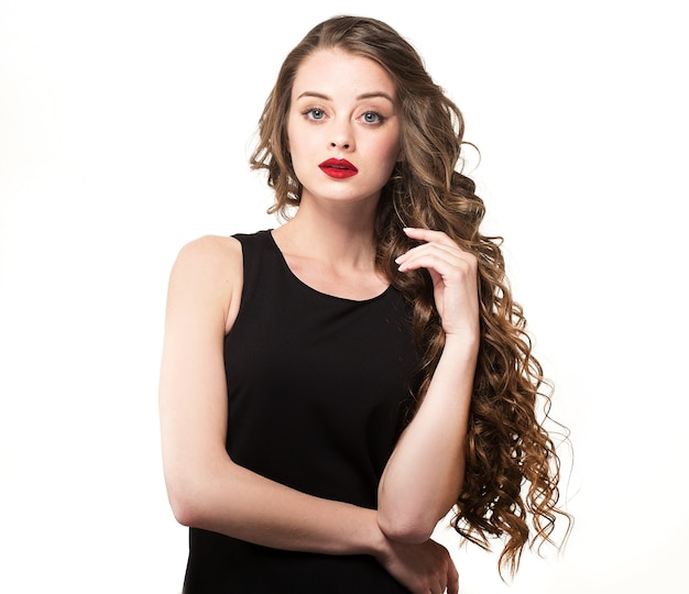 Portrait femme belle sensualité en robe noire avec de longs cheveux bouclés posant sur fond blanc