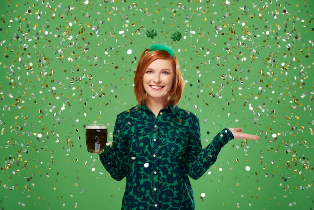 Portrait de femme avec de la bière sous une douche de confettis