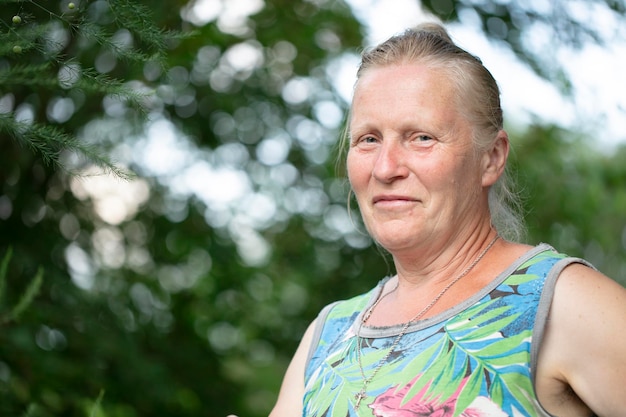 Portrait d'une femme blonde âgée d'apparence normale sur fond de verdure