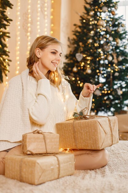 Portrait d'une femme blonde assise près de l'arbre de Noël