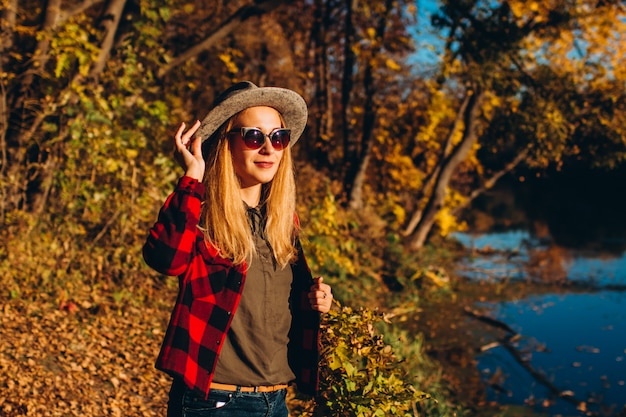 Portrait d'une femme blonde au chapeau gris dans la forêt d'automne