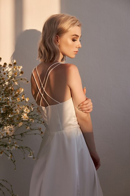 Portrait d'une femme blonde dans une robe de mariée blanche au soleil du soir