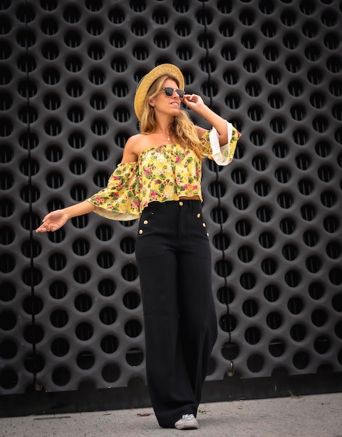 Portrait d'une femme blonde dans une tenue jaune vintage avec un chapeau sur une photo verticale de fond noir