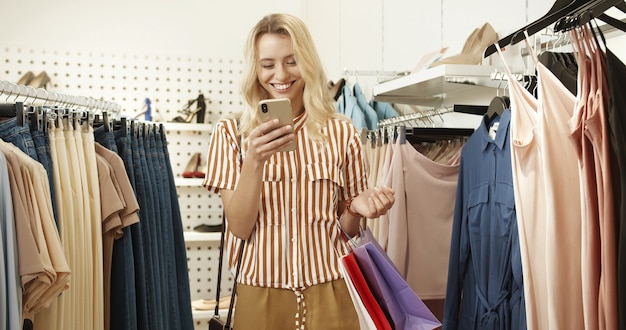 Portrait d'une femme blonde debout dans un magasin de vêtements