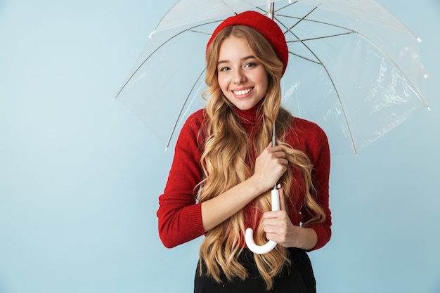 Portrait de femme blonde joyeuse des années 20 aux cheveux longs debout sous le parapluie tout en isolé