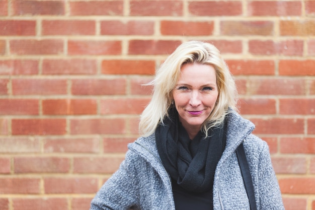 Portrait d&#39;une femme blonde avec mur de briques