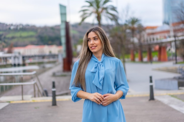 Portrait de femme blonde en robe bleue marchant le long de la rivière dans le concept de style de vie de la ville