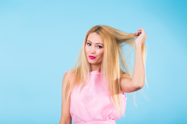 Portrait de femme blonde souriante au look à la mode sur le mur bleu. Concept de style, mode, été et personnes.