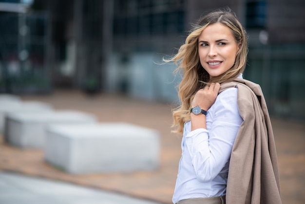 Portrait d'une femme blonde souriante marchant dans un quartier de la ville