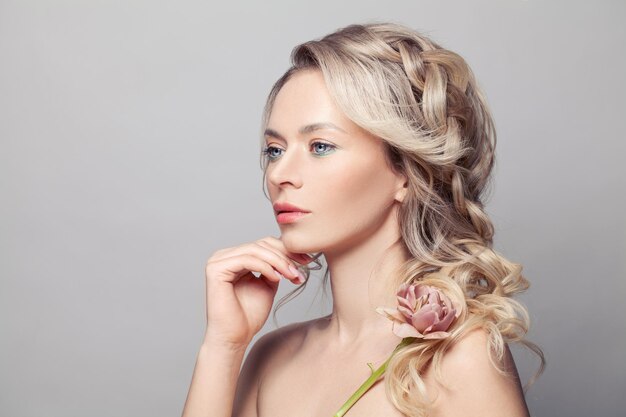 Portrait d'une femme blonde touchant une peau saine sur fond blanc en studio Concept de soin de la peau