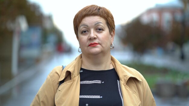 Portrait d'une femme bouleversée triste debout dans la rue et regardant la caméra