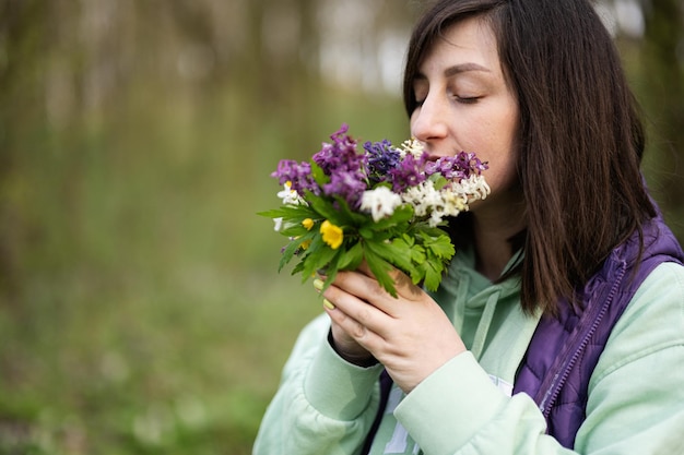 Portrait de femme avec bouquet de fleurs de printemps sur la forêt Concept de loisirs en plein air