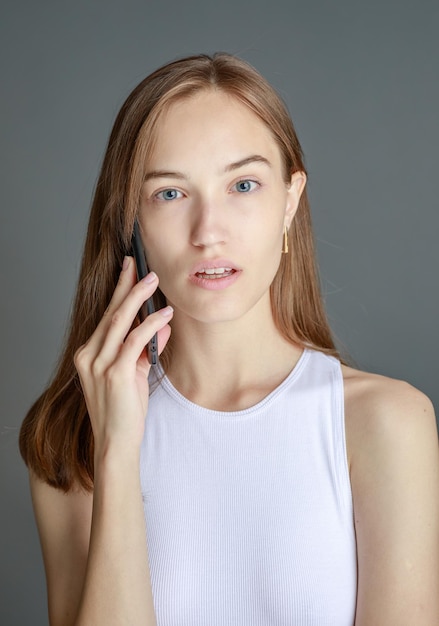 Photo portrait d'une femme brune de 20 ans utilisant un téléphone portable tout en se tenant isolé sur fond jaune