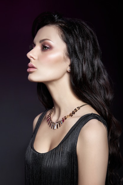 Portrait d'une femme brune avec une coiffure chic et un collier autour du cou