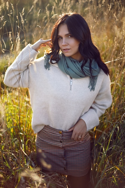 Portrait d'une femme brune dans un pull et une écharpe en automne dans un champ