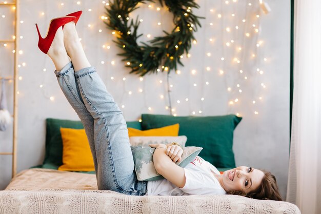 Portrait de femme brune magnifique en talons hauts rouges s'amuse au lit