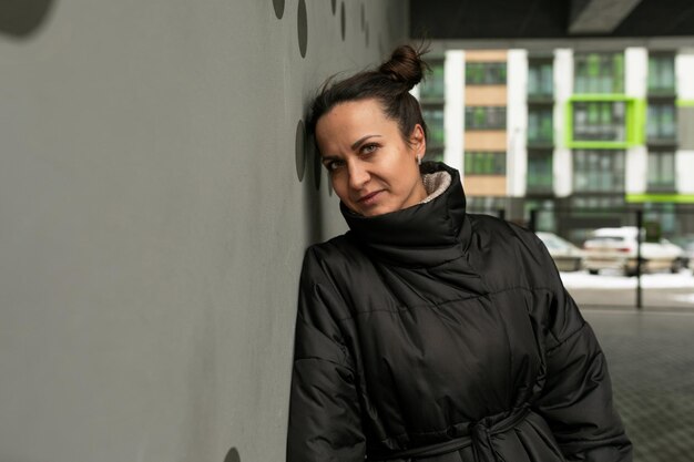 Portrait d'une femme brune mignonne et heureuse contre un mur noir