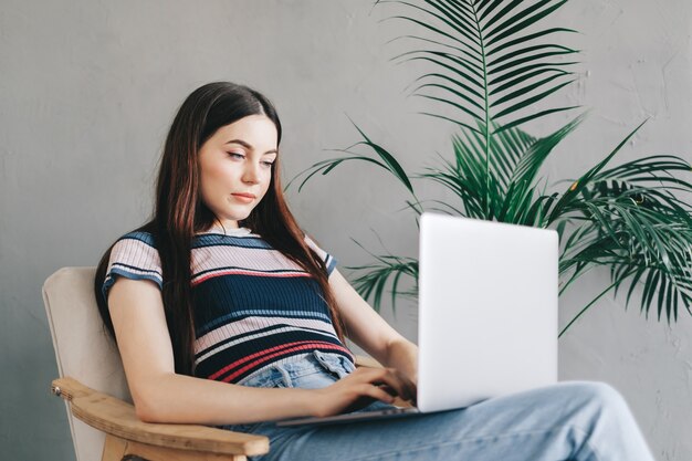 Portrait de femme brune, pigiste travaillant à distance à la maison, regardant l'écran du portable