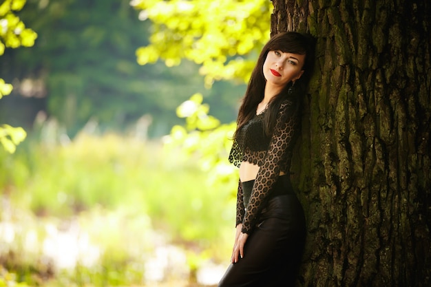 Portrait d'une femme brune près d'un arbre