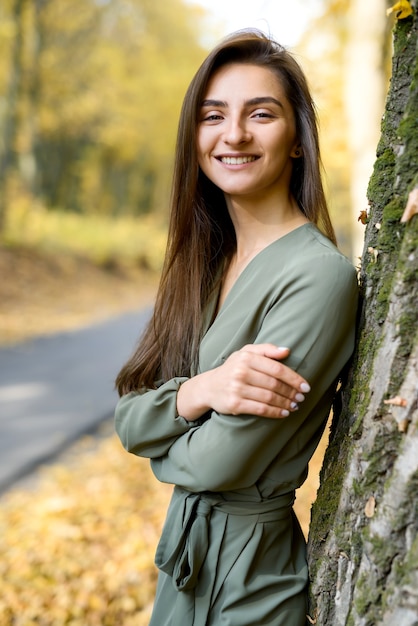 Portrait de femme brune en robe verte posant en automne parc