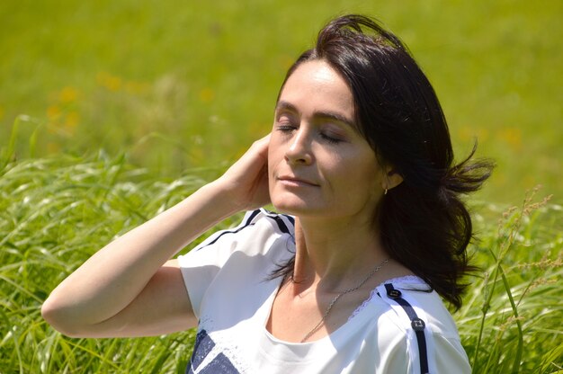 Portrait de femme brune russe avec les yeux fermés sur un champ vert