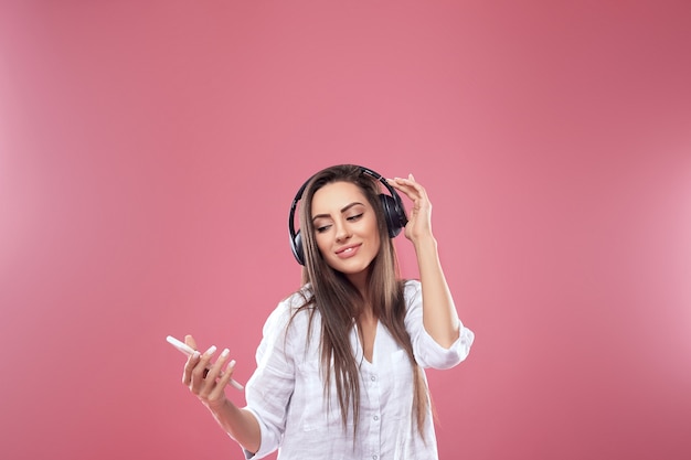 Portrait de femme brune souriante dans les écouteurs avec smartphone écoute de la musique