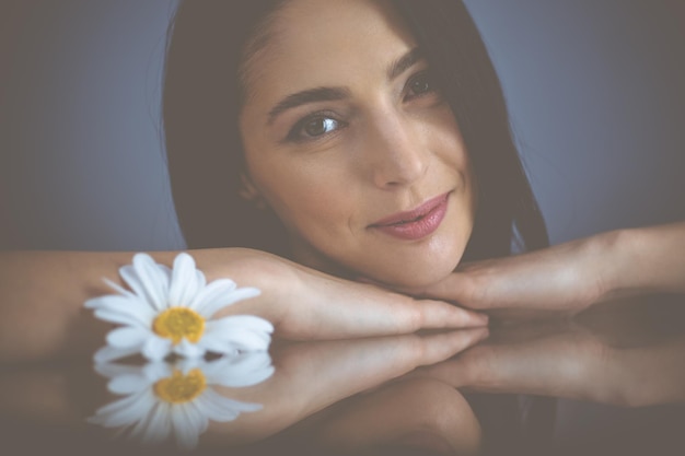 Portrait d'une femme brune souriante regardant la caméra.