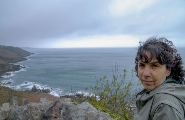 Portrait de femme brune, vent dans les cheveux, près de la mer