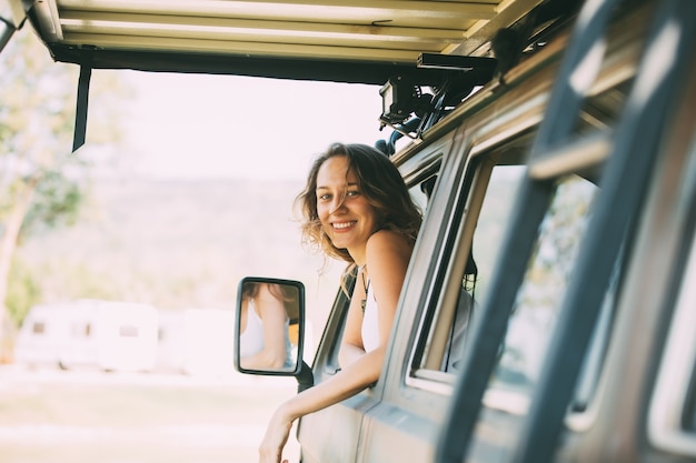 Portrait femme caucasienne heureuse conduit un vieux camping-car vintage sur route.