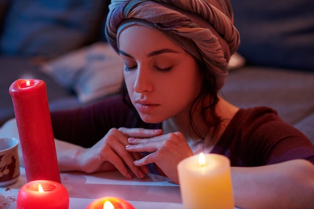 Portrait d'une femme caucasienne placide dans le couvre-chef pratiquant la médiation avant un rituel magique