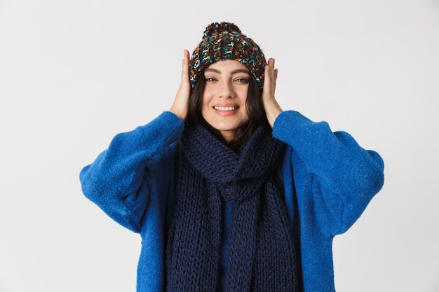 Portrait de femme caucasienne portant un chapeau d'hiver et enveloppé dans une écharpe chaude debout, isolé sur blanc