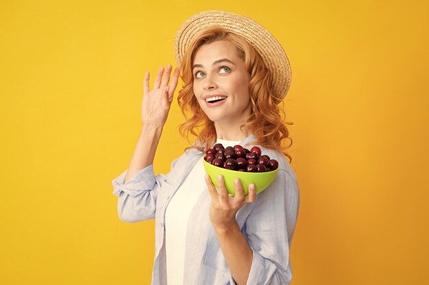 Portrait de femme avec des cerises sur fond jaune studio isolé