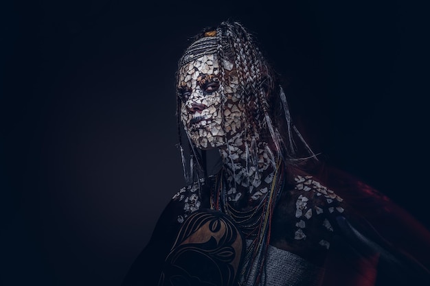 Portrait d'une femme chaman africaine effrayante avec une peau fissurée pétrifiée et des dreadlocks sur fond sombre. Notion de maquillage.