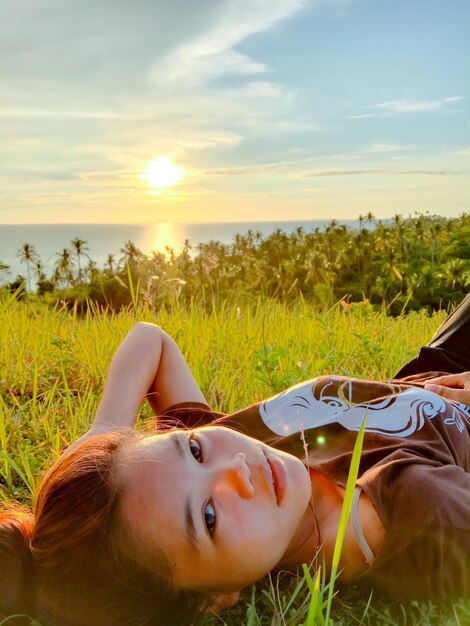 Photo portrait d'une femme sur un champ contre le ciel au coucher du soleil