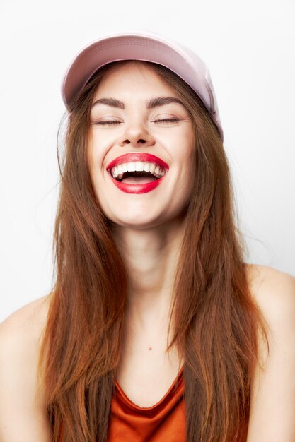 Portrait d'une femme avec un chapeau qui rit avec les yeux fermés charme robe rouge gros plan